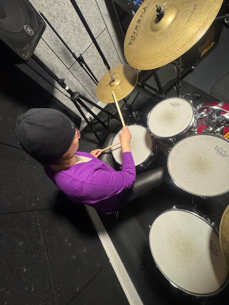 Nath spielt Schlagzeug, dynamisch von oben fotografiert