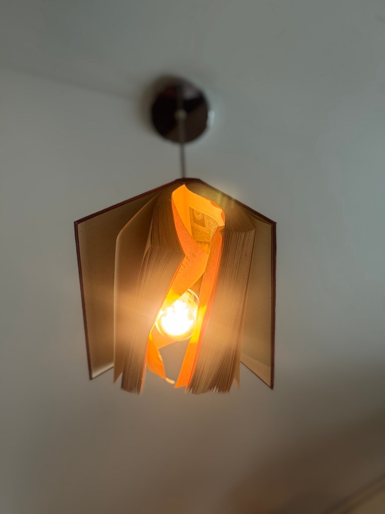 Eine Deckenlampe mit einem Schirm, der aus einem alten Buch gebastelt wurde